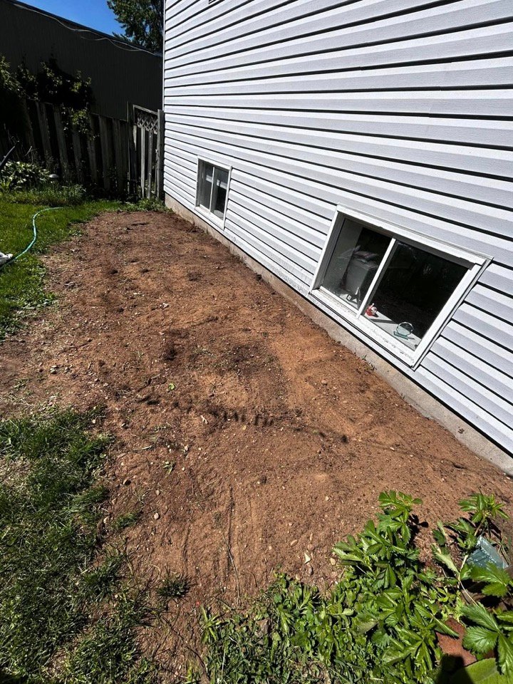 Bare dirt patch prepped along a house foundation before sodding